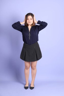 Mor arka planda sıradan kıyafetlerle duran tombul Asyalı kadın..