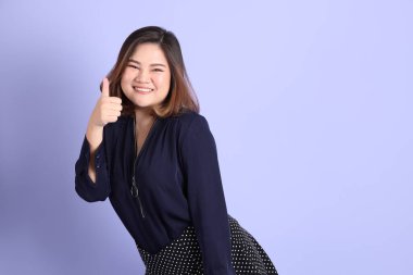 Mor arka planda sıradan kıyafetlerle duran tombul Asyalı kadın..