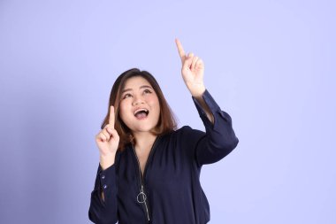 Mor arka planda sıradan kıyafetlerle duran tombul Asyalı kadın..