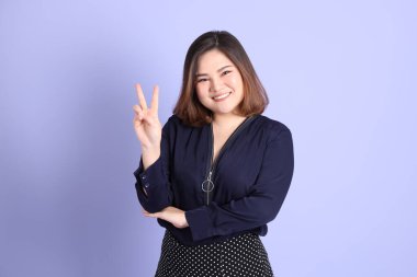 Mor arka planda sıradan kıyafetlerle duran tombul Asyalı kadın..