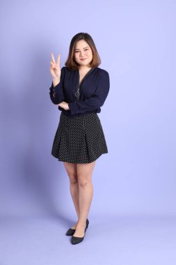 Mor arka planda sıradan kıyafetlerle duran tombul Asyalı kadın..