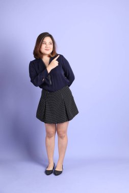 Mor arka planda sıradan kıyafetlerle duran tombul Asyalı kadın..