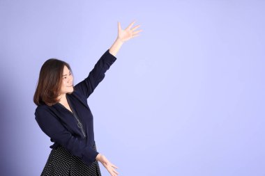 Mor arka planda sıradan kıyafetlerle duran tombul Asyalı kadın..