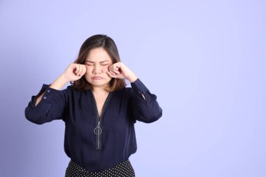 Mor arka planda sıradan kıyafetlerle duran tombul Asyalı kadın..