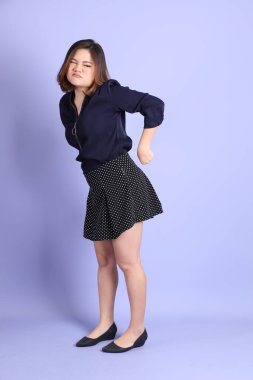 Mor arka planda sıradan kıyafetlerle duran tombul Asyalı kadın..