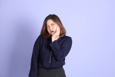 Mor arka planda sıradan kıyafetlerle duran tombul Asyalı kadın..