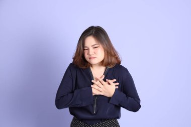 Mor arka planda sıradan kıyafetlerle duran tombul Asyalı kadın..