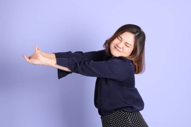 Mor arka planda sıradan kıyafetlerle duran tombul Asyalı kadın..