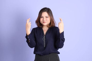 Mor arka planda sıradan kıyafetlerle duran tombul Asyalı kadın..