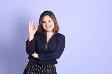 Mor arka planda sıradan kıyafetlerle duran tombul Asyalı kadın..