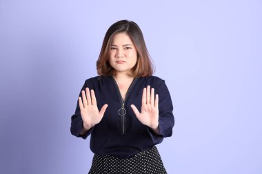 Mor arka planda sıradan kıyafetlerle duran tombul Asyalı kadın..