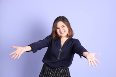 Mor arka planda sıradan kıyafetlerle duran tombul Asyalı kadın..