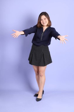 Mor arka planda sıradan kıyafetlerle duran tombul Asyalı kadın..