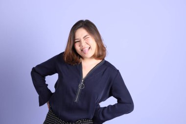 Mor arka planda sıradan kıyafetlerle duran tombul Asyalı kadın..