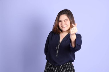 Mor arka planda sıradan kıyafetlerle duran tombul Asyalı kadın..