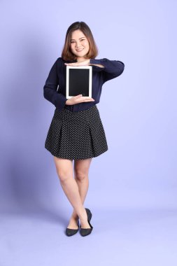 Mor arka planda sıradan kıyafetlerle duran tombul Asyalı kadın..