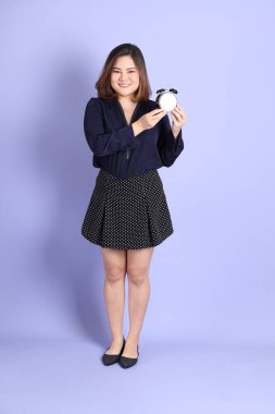 Mor arka planda sıradan kıyafetlerle duran tombul Asyalı kadın..