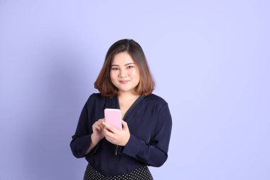 Mor arka planda sıradan kıyafetlerle duran tombul Asyalı kadın..