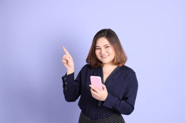 Mor arka planda sıradan kıyafetlerle duran tombul Asyalı kadın..