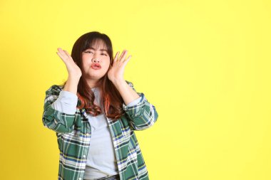 Sarı arka planda sıradan kıyafetlerle duran tombul Asyalı kadın..