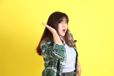 Sarı arka planda sıradan kıyafetlerle duran tombul Asyalı kadın..