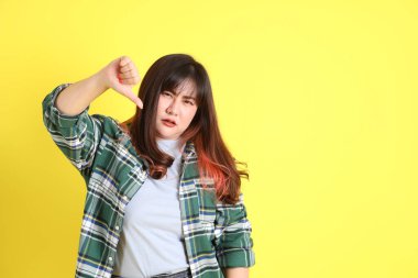 Sarı arka planda sıradan kıyafetlerle duran tombul Asyalı kadın..