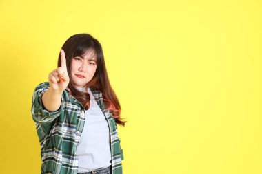 Sarı arka planda sıradan kıyafetlerle duran tombul Asyalı kadın..