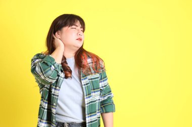 Sarı arka planda sıradan kıyafetlerle duran tombul Asyalı kadın..