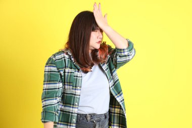 Sarı arka planda sıradan kıyafetlerle duran tombul Asyalı kadın..