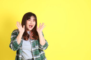 Sarı arka planda sıradan kıyafetlerle duran tombul Asyalı kadın..