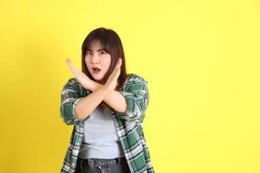 Sarı arka planda sıradan kıyafetlerle duran tombul Asyalı kadın..