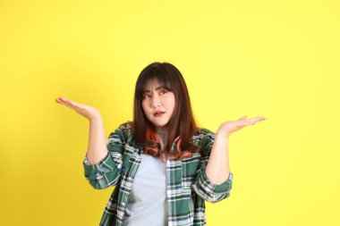 Sarı arka planda sıradan kıyafetlerle duran tombul Asyalı kadın..