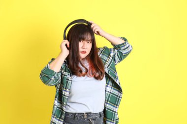 Sarı arka planda sıradan kıyafetlerle duran tombul Asyalı kadın..