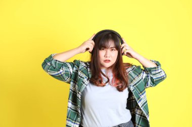 Sarı arka planda sıradan kıyafetlerle duran tombul Asyalı kadın..