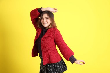 Sarı arka planda sıradan kıyafetlerle duran tombul Asyalı kadın..