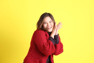 Sarı arka planda sıradan kıyafetlerle duran tombul Asyalı kadın..