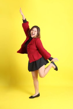 Sarı arka planda sıradan kıyafetlerle duran tombul Asyalı kadın..