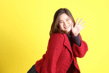 Sarı arka planda sıradan kıyafetlerle duran tombul Asyalı kadın..