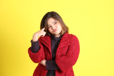 Sarı arka planda sıradan kıyafetlerle duran tombul Asyalı kadın..