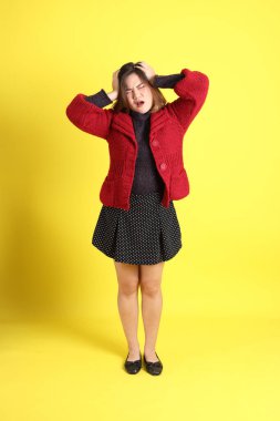 Sarı arka planda sıradan kıyafetlerle duran tombul Asyalı kadın..