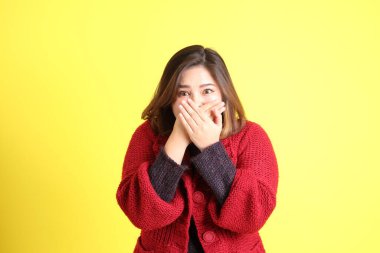 Sarı arka planda sıradan kıyafetlerle duran tombul Asyalı kadın..