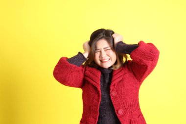 Sarı arka planda sıradan kıyafetlerle duran tombul Asyalı kadın..