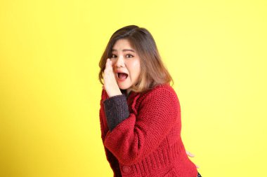 Sarı arka planda sıradan kıyafetlerle duran tombul Asyalı kadın..