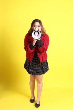 Sarı arka planda sıradan kıyafetlerle duran tombul Asyalı kadın..