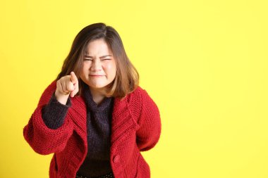 Sarı arka planda sıradan kıyafetlerle duran tombul Asyalı kadın..