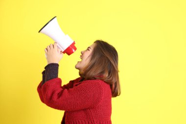 Sarı arka planda sıradan kıyafetlerle duran tombul Asyalı kadın..