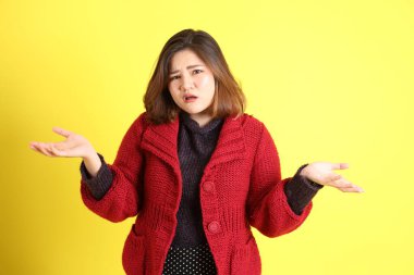 Sarı arka planda sıradan kıyafetlerle duran tombul Asyalı kadın..