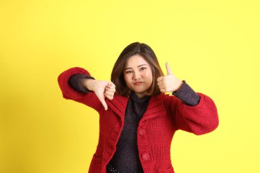 Sarı arka planda sıradan kıyafetlerle duran tombul Asyalı kadın..