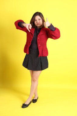 Sarı arka planda sıradan kıyafetlerle duran tombul Asyalı kadın..