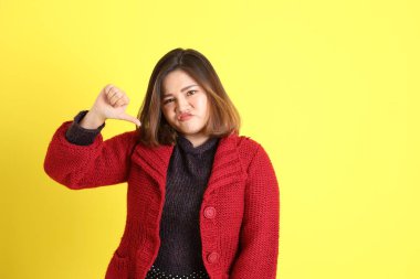 Sarı arka planda sıradan kıyafetlerle duran tombul Asyalı kadın..